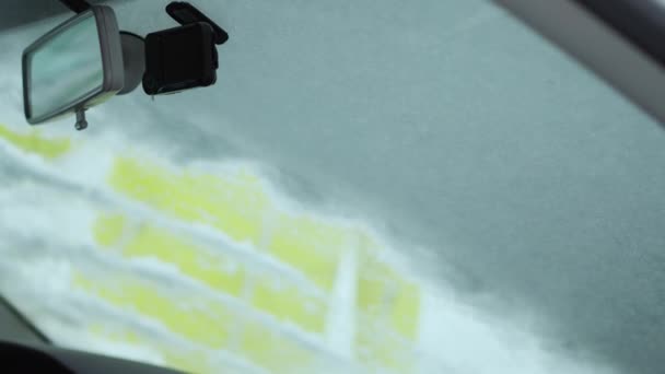 Het schrapen van sneeuw en ijs van de voorruit van de auto. Ruitenwissers verhoogd de avond tevoren te voorkomen dat ze steeds bevroren. Winter rijden — Stockvideo