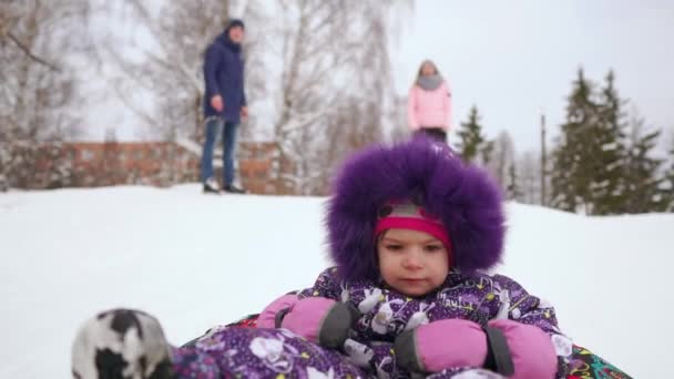 Счастливые мама и дочь катаются на санках зимой в снегу и играют в снежки. мать и ребенок смеются и радуются скольжению по надувной трубке. Семейные игры парк во время рождественских каникул. Медленное движение — стоковое видео