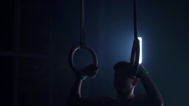 Gymnast on a dark background stands on his hands using rings in the air. Performs rotation in the Olympic program in slow motion 120 fps. gymnastic rings, professional gymnast — Stock Video