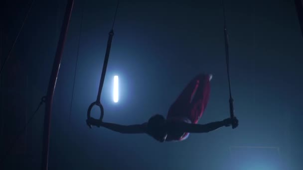 Manliga gymnast idrottsman utför handstående och rotation på ringar på mörk bakgrund och rök i slow motion — Stockvideo