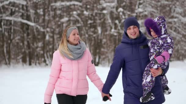 夕暮れ時の幸せな家族。父、母と子供 2 人の娘は楽しんで、自然の雪に覆われた冬の散歩で遊んでいます。子供は父親の肩の上に座っています。霜冬のシーズン. — ストック動画