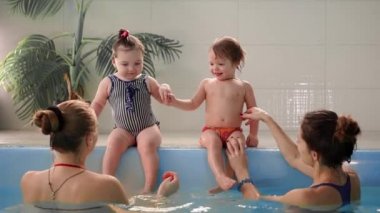 İki bebek havuzda gülmek ve ellerini alkışlar suya atlamak