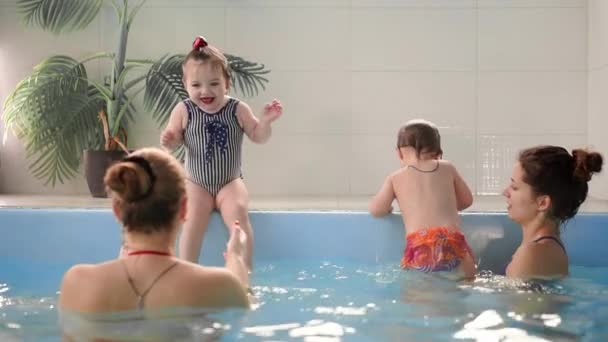 Happy middle-aged mother swimming with cute adorable baby in swimming pool. Smiling mom and little child, newborn girl having fun together. Active family spending leisure and time in spa hotel. — Stock Video