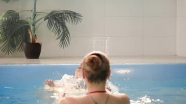 Mutlu gülümseyerek yürümeye başlayan çocuk atlama ve yüzme havuzunda su altında dalış. Sualtı bir atış. Slowmotion