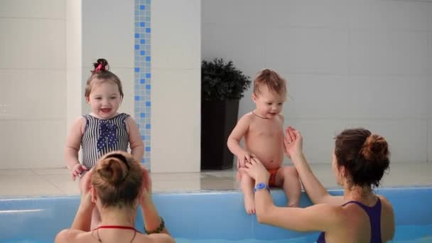 İki bebek havuzda gülmek ve ellerini alkışlar suya atlamak — Stok video