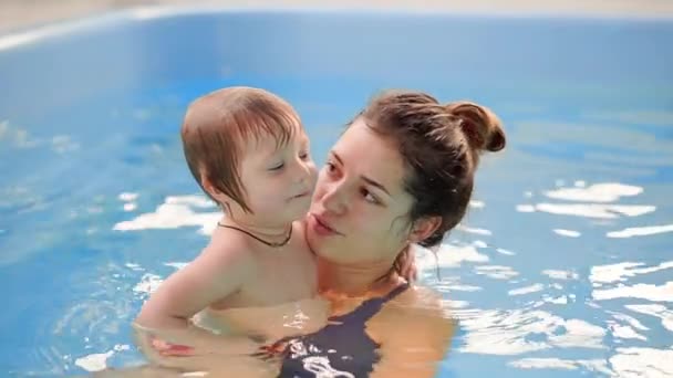 Молодая мама в бассейне играет со своей маленькой дочерью в замедленной съемке. Спортивная семья ведет активный образ жизни — стоковое видео