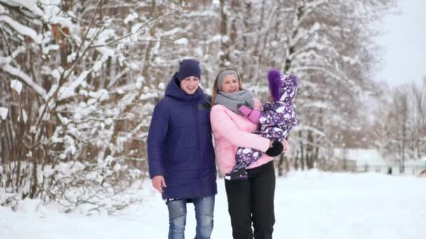 夕暮れ時の幸せな家族。父、母と子供 2 人の娘は楽しんで、自然の雪に覆われた冬の散歩で遊んでいます。子供は父親の肩の上に座っています。霜冬のシーズン. — ストック動画