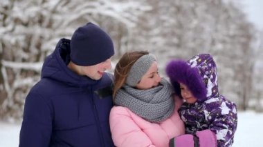 Gün batımında mutlu bir aile. Baba, anne ve iki çocuk kızı eğleniyor ve karlı kış yürüyüş doğada oynamaya. Çocuk babasının omuzlarında oturur. Frost kış sezonu.