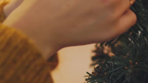 Mano de mujer decorando árbol de Navidad con luces brillantes de Navidad . — Vídeos de Stock