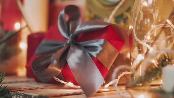 Pasatiempo creativo. Envoltura de regalo. Embalaje modernas cajas de regalo de Navidad en papel gris con estilo con cinta de satén rojo. Vista superior de las manos en la mesa de madera blanca con ramas de abeto, decoración — Vídeo de stock