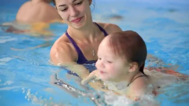 Glad medelålders mor simning med söt bedårande baby i poolen. Ler mamma och lilla barn, nyfödd tjej att ha roligt tillsammans. Aktiv familj spendera fritid och tid i spa hotel. — Stockvideo