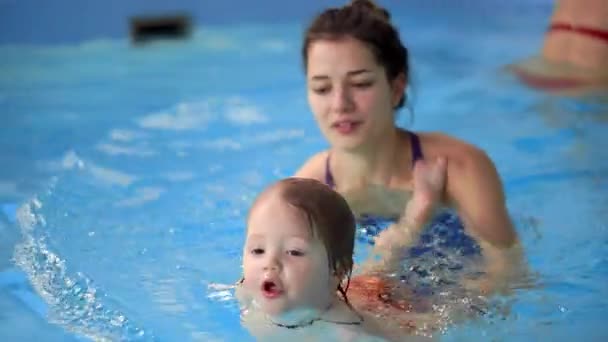Criança sorridente feliz está pulando e mergulhando sob a água na piscina. Um tiro subaquático. Movimento lento — Vídeo de Stock