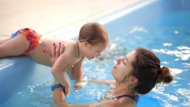 Bebé en la piscina saltando desde el lado en el agua y nada a su madre en cámara lenta — Vídeo de stock