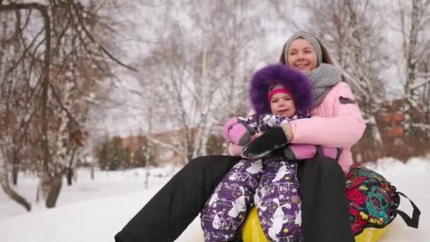 幸せなママと娘雪で冬のそりや雪玉を再生します 母と子が笑うし インフレータブル チューブのグライドを喜ぶ 家族は クリスマス休暇中に公園を再生します スローモーション — ストック動画