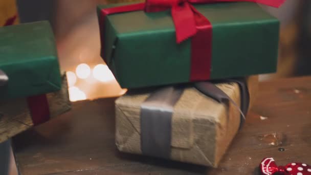 Mooi geschenk in de handen van mannen. Nieuwe jaar cadeau met een rood lint, spar op tafel. De man maakte het zichzelf en gaat geven voor de vakantie. Mooie achtergrond met open haard. — Stockvideo