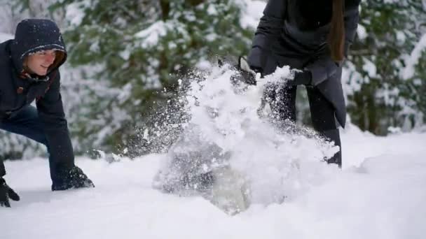 Man en vrouw veel plezier bij het wandelen met de Siberische husky in winter bos spelen en gooien van sneeuw — Stockvideo