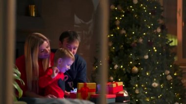 Anne baba ve oğul evde açık hediyeler Noel, Noel iç kanepede oturuyor. Sıcak ve rahat ev atmosfer