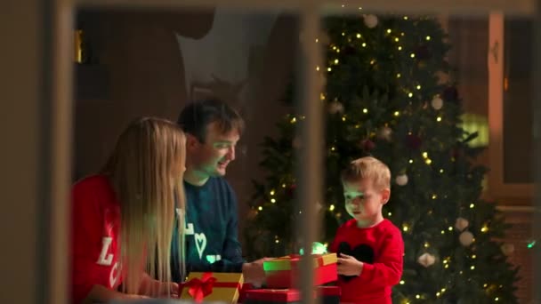 Retrato de familia feliz abriendo una caja de regalo de Navidad por la noche. Concepto de vacaciones, sorpresa, familia feliz, comercio electrónico, compras en línea . — Vídeos de Stock