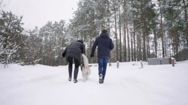İnsanlar ormandaki bir yolda. Bir adam ve bir Sibirya Husky köpek ormandaki karda bir çocukla bir atlı kızak çekerek vardır. Bir kadın ormanda yürüyor