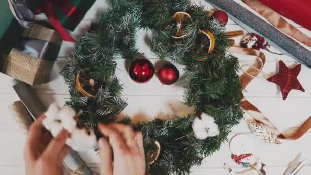Вид сверху Рождественский венок на фоне ремесла, довольно Famale руки украсить рождественский венок, съемка движения — стоковое видео