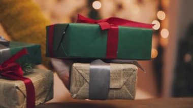 Yaratıcı hobi. Hediye. Saten kurdele ile şık gri kağıt modern Noel hediyesi ambalaj kutuları. Eller üstten görünüm köknar ağacı dalları, dekorasyon Beyaz ahşap tablo