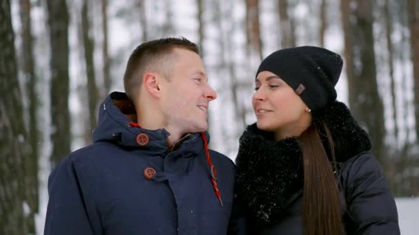 Primer plano de un hombre y una mujer enamorados de pie en el bosque de invierno abrazándose y mirando a la distancia — Vídeo de stock