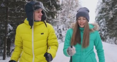 Gülümseyen adam ağır çekimde ormanda sevgi dolu eşi ile Kayak Kış ceket. Sağlıklı bir yaşam tarzı. Genç çift