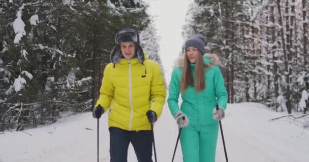 Fotografía en cámara lenta de una pareja amorosa esquiando en el bosque en la víspera del día de San Valentín — Vídeo de stock