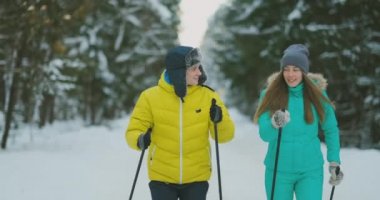 Evli bir çift portresi. Sarı Ceket ve ormanda ağır çekimde kayak kış mavi tulum bir kadında erkekte