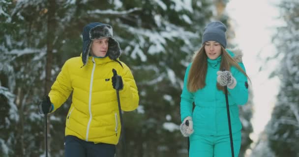 Amar al hombre y a la mujer en cámara lenta en invierno esquiando en el bosque. San Valentín — Vídeo de stock