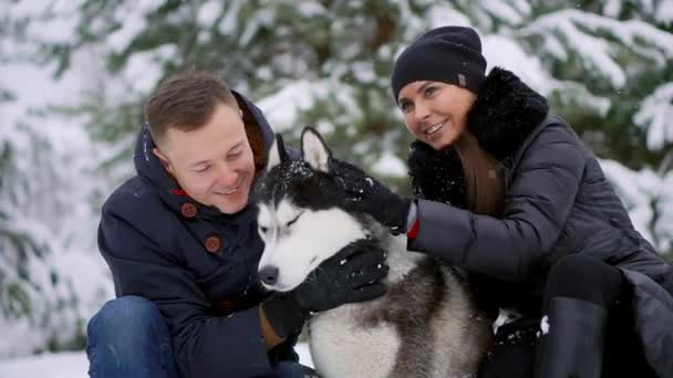 Vrouw en man spelen met de hond in de sneeuw. — Stockvideo