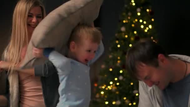 La familia pasa tiempo libre en casa. Familia alegre divirtiéndose con su hijo en la cama. En la víspera de Navidad y Año Nuevo . — Vídeo de stock