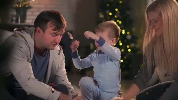 La familia pasa tiempo libre en casa. Familia alegre divirtiéndose con su hijo en la cama. En la víspera de Navidad y Año Nuevo . — Vídeo de stock