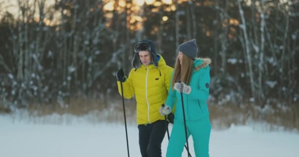 Pełnej długości dziewczyna portret człowieka pomaga rannych podczas narciarskich spacer w lesie zimą — Wideo stockowe