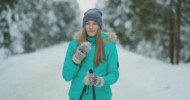 笑顔の美しい若い女性の肖像画を腰で雪に覆われた冬の森、スキーを楽しみながらカメラ見て喜んでスペースをコピーします。 — ストック動画