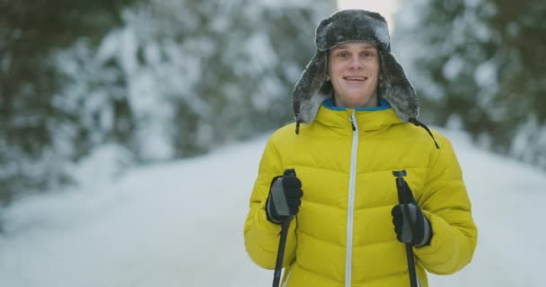 Homem sorridente com esquis e sua esposa olhando para algo curioso durante a viagem na floresta de inverno — Vídeo de Stock