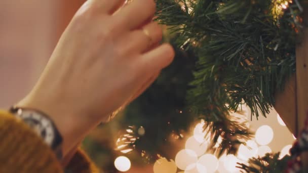 Mujer de la mano decorando en el árbol de Navidad con luces brillantes de Navidad . — Vídeo de stock