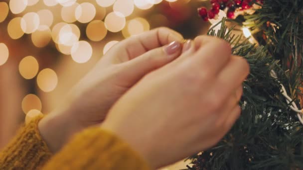 Hand einer Frau schmückt Weihnachtsbaum mit Weihnachtsbeleuchtung. — Stockvideo