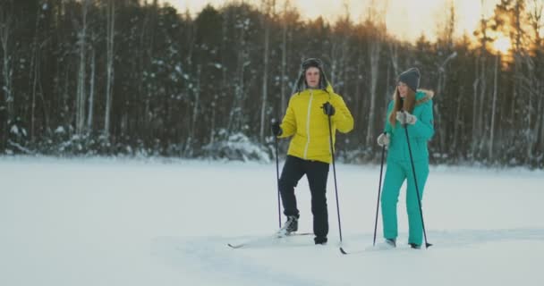 V zimním lese při západu slunce milující pár lyžování a podívat se na krásy přírody a atrakcí v pomalém pohybu. — Stock video