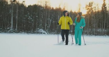 Sarı ceket ve ağır çekimde günbatımında Kayak mavi tulum bir kızda erkekte