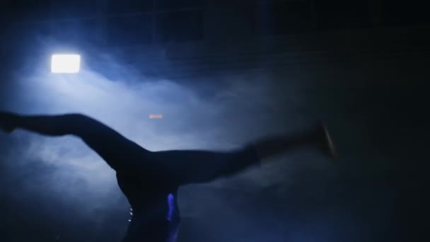 Ginasta menina executa um salto mortal no tapete de ginástica em câmera lenta na luz de fundo — Vídeo de Stock