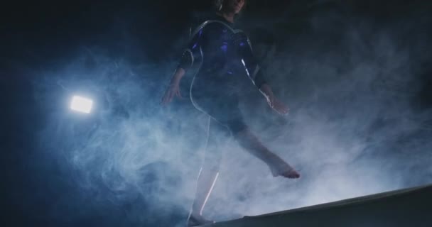 Close-up of the leg of a girl gymnast perform a balance beam jump in smoke and slow motion. — Stock Video