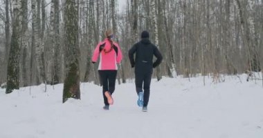Erkek ve kadın ağır çekimde parkın içinden çalışan kışın.