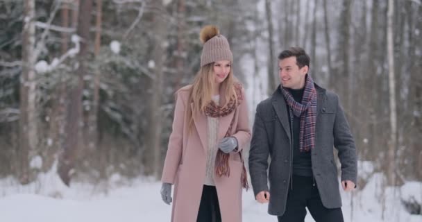 Jong getrouwd paar boswandelingen de winter. Een man en een vrouw kijken elkaar lachen en glimlachen in slow motion. — Stockvideo