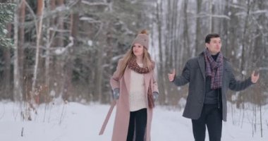 Genç bir adam ve bir kadın bir ceket eğleniyor ve yavaş bir kış orman karda oynarken. Mutluluk ve yüzler gülümsüyor