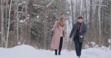 Genç evli çift Kış ormanda yürüyüş seviyorum. Bir erkek ve bir kadın birbirlerini gülüyor ve ağır çekimde gülümseyerek bak. Sevgililer günü aşk hikayesi.