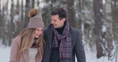 Genç çift yürür kış orman evli. Bir erkek ve bir kadın birbirlerini gülüyor ve ağır çekimde gülümseyerek bak.