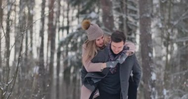 Genç bir adam ve bir kadın bir ceket eğleniyor ve yavaş bir kış orman karda oynarken. Mutluluk ve yüzler gülümsüyor