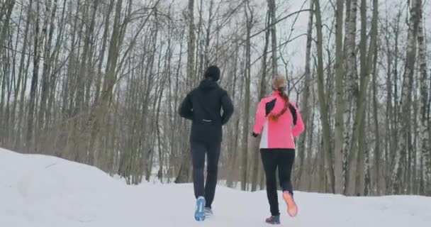 Krásná žena a muž jsou spuštěny v lese v zimě správné výživy a zdravého životního stylu. Zpomalený pohyb. — Stock video