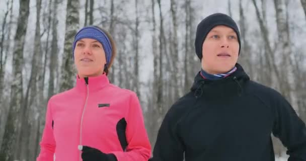 Egy gyönyörű nő és egy férfi fut az erdőben, a téli megfelelő táplálkozás és az egészséges életmód. Lassú mozgás. — Stock videók